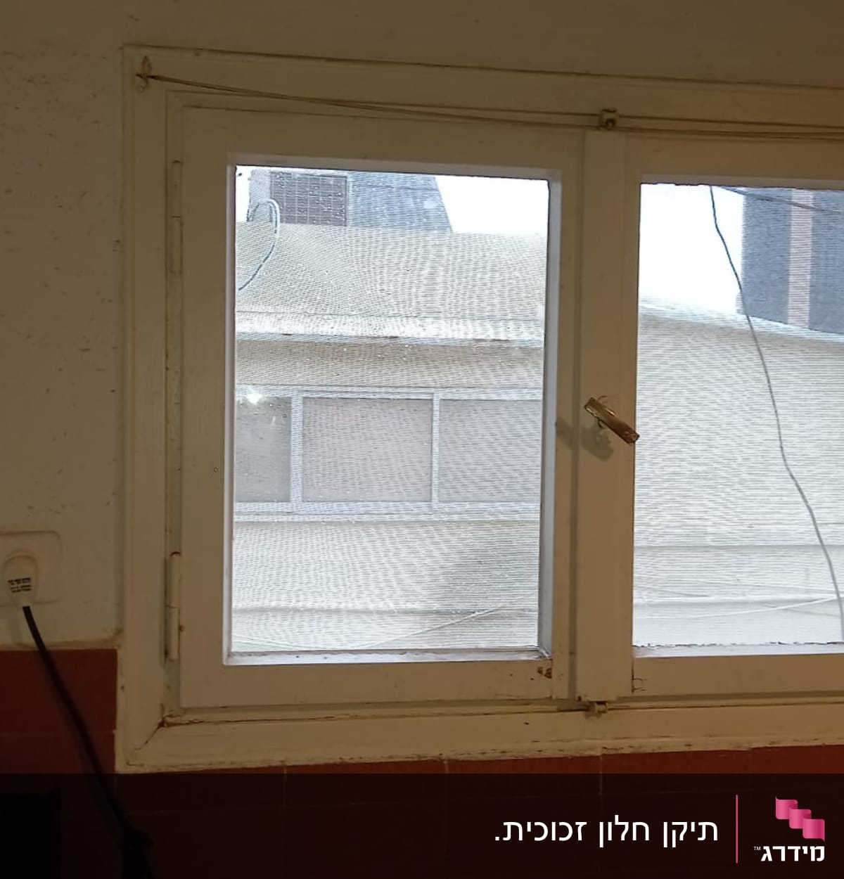 חלון זכוכית עם מסגרת לבנה וקיר חיצוני ברקע